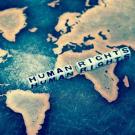 A blue and yellow portion of a world map, with the words "Human Rights" written in dice placed on top of the map.